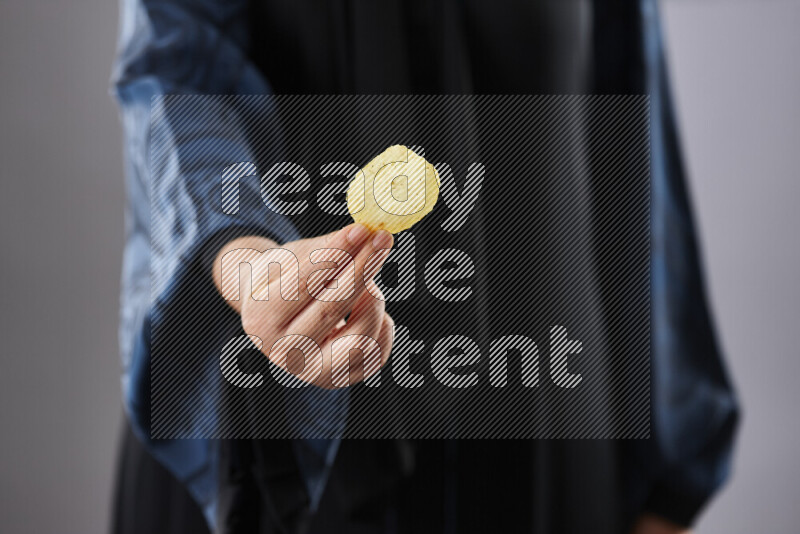 Woman in abaya holding different kinds of snacks in different positions