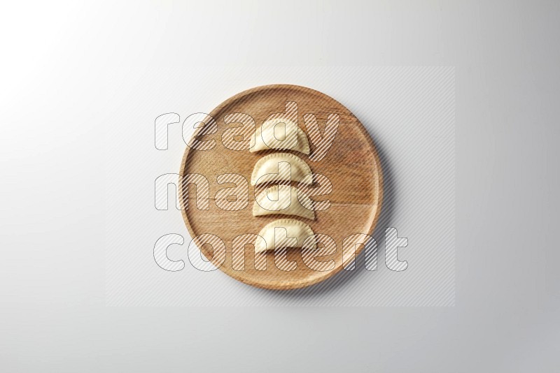 Four Sambosas on a wooden round plate on a white background