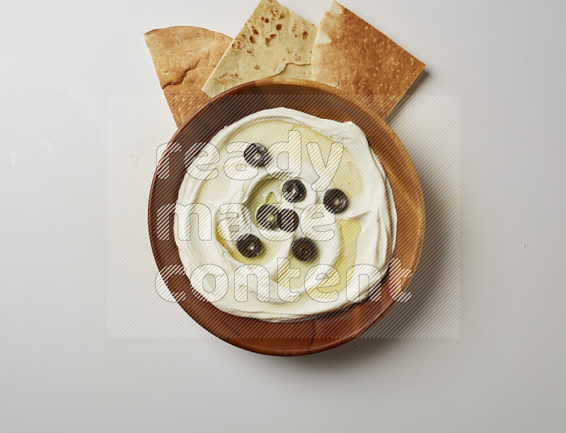 Lebnah garnished with sliced olives in a wooden plate on a white background