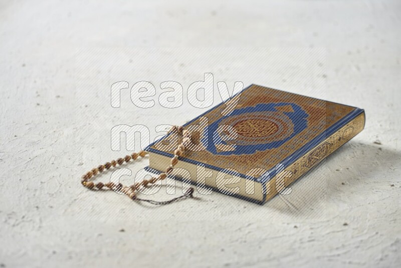 Quran with dates, prayer beads and different drinks all placed on textured white background