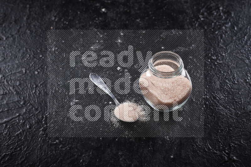 وعاء زجاجي ممتلئ بملح الهيمالايا الناعم على خلفية سوداء