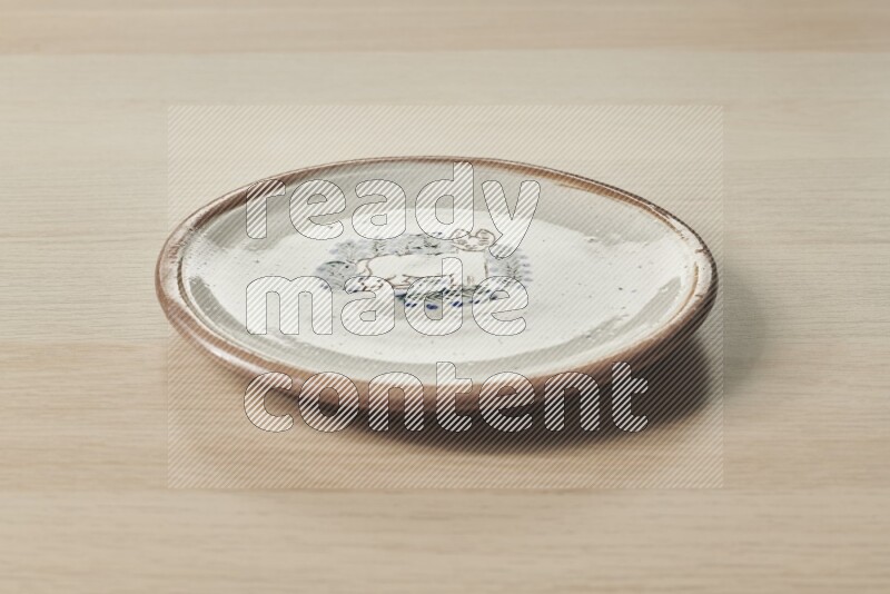 A decorative pottery plate on light wooden background