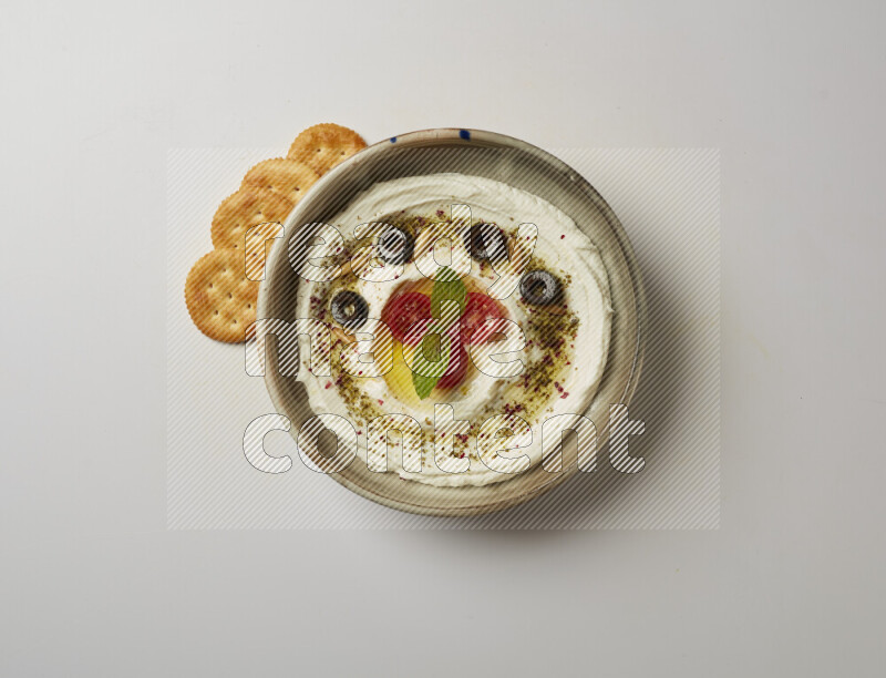 Lebnah garnished with cherry tomato, mint, olives & pine nuts in a grey pottery plate on a white background