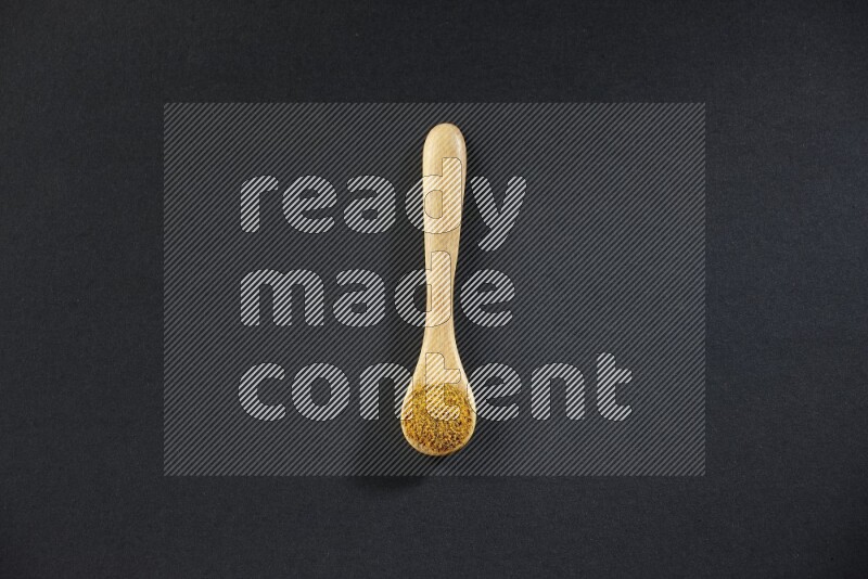 ملعقة خشبية ممتلئة ببودرة الكركم على خلفية سوداء