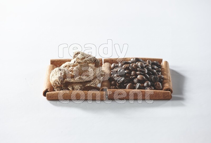 مربعان من أعواد القرفة ممتلئان بحبوب القهوة والزنجبيل المجفف علي خلفية بيضاء