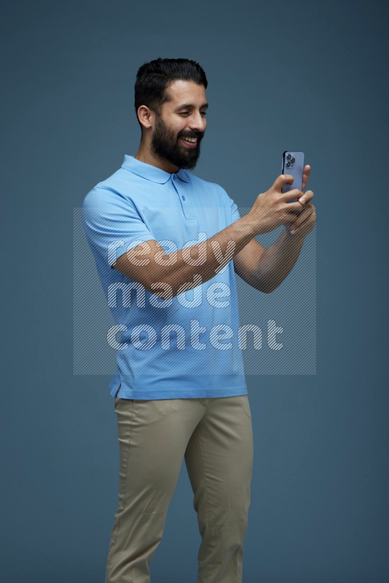 Man taking a picture with his phone  in a blue background wearing a Blue shirt