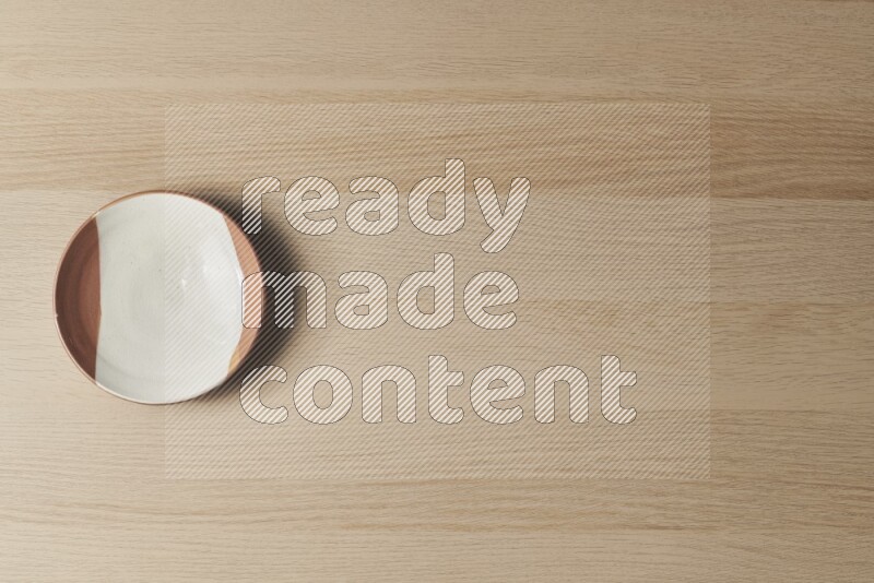 A multicolored pottery plate on light wooden background