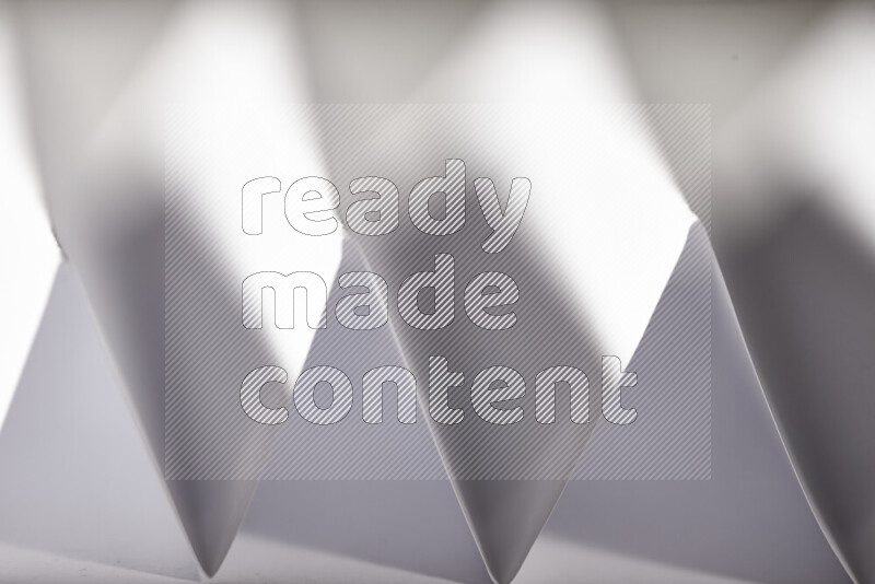 A close-up abstract image showing sharp geometric paper folds in grey gradients