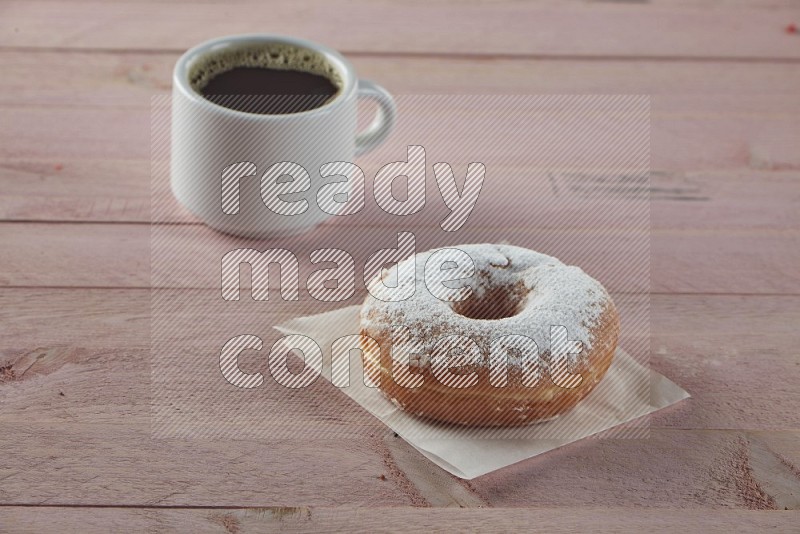 Sugar dusted doughnut on pink wooden background