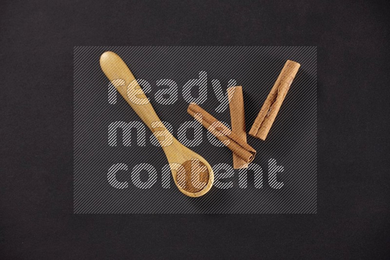 3 Cinnamon sticks stacked beside a wooden spoon full of cinnamon powder on black background in different angles