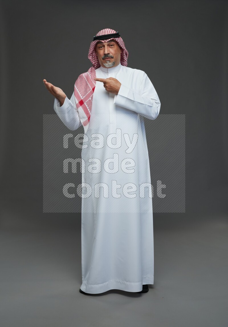 Saudi man with shomag Standing Interacting with the camera on gray background