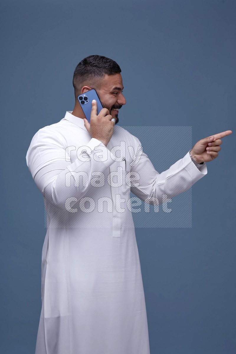 رجل سعودي يرتدي ثوب ابيض ويتحدث في جواله