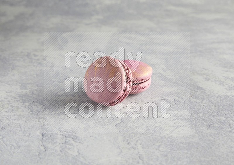 45º Shot of two Purple Strawberry macarons on white  marble background