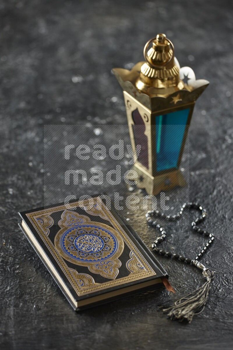 A golden lantern with different drinks, dates, nuts, prayer beads and quran on textured black background