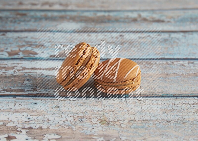 45º Shot of of two assorted Brown Irish Cream, and Brown Maple Taffy macarons  on light blue background