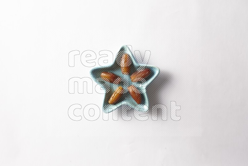 Libyan dates in a star shaped pottery plate on white background
