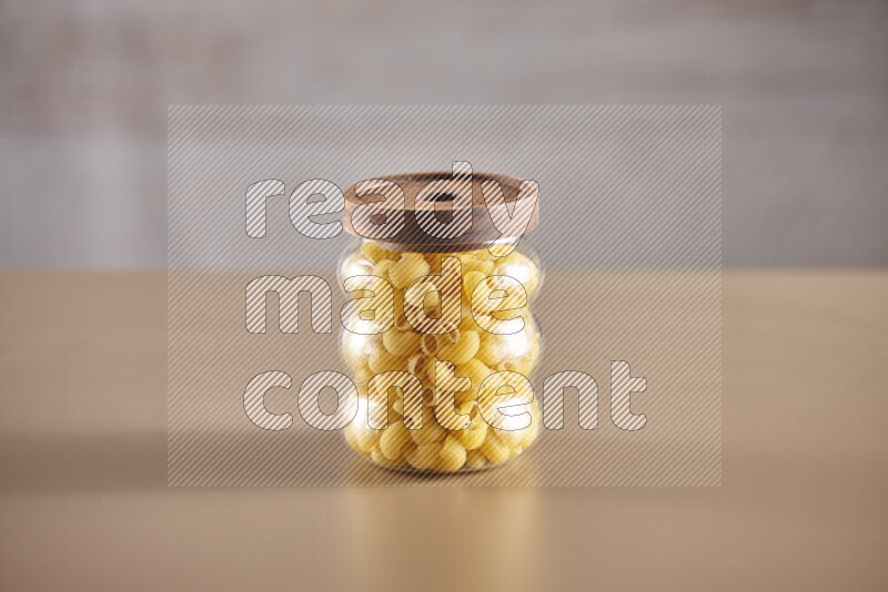 Raw pasta in glass jars on beige background