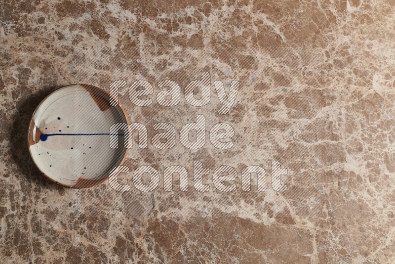 A multicolored pottery plate on beige marble background