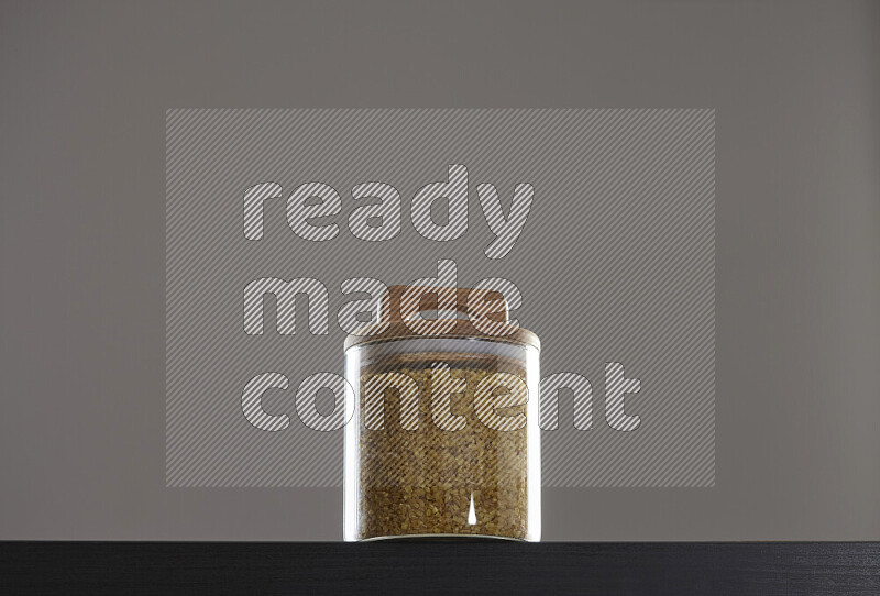 Coarse bulgur in a glass jar on black background