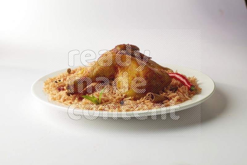 red basmati Rice with kabsa chicken pieces on a white rounded plate direct on white background