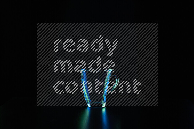 Glassware with rim light in blue and green against black background