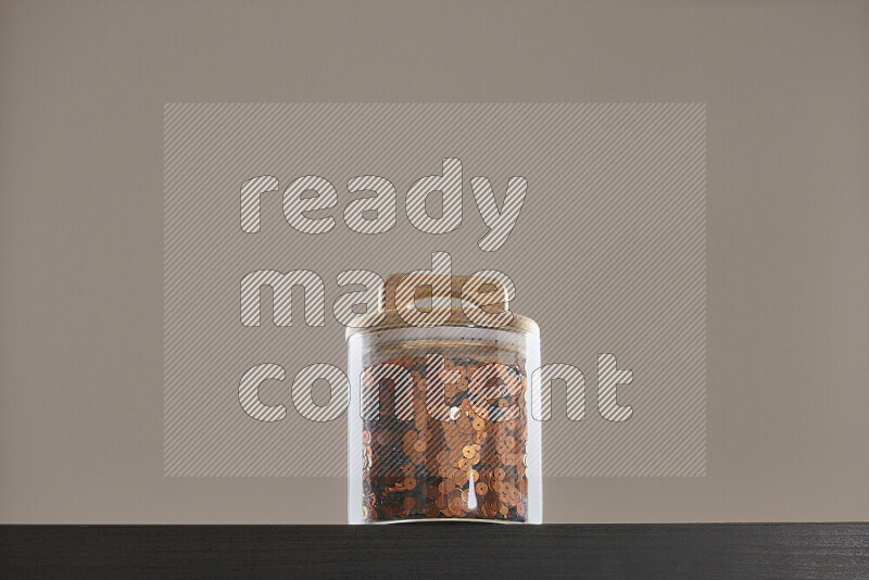 Sequins in a glass jar on black background