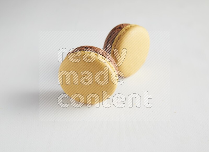 45º Shot of two Yellow and Brown Chai Latte macarons on white background