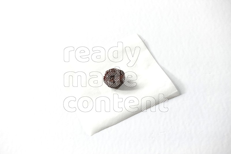 حبة واحدة من البرقوق المجفف على قطعة من الورق على خلفية بيضاء