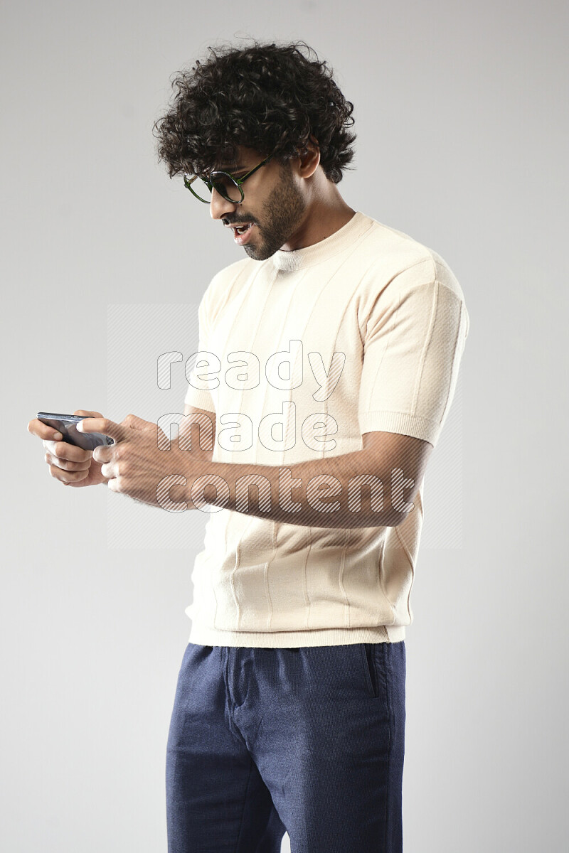 رجل يرتدي ملابس كاجوال يلعب علي الهاتف علي خلفية بيضاء
