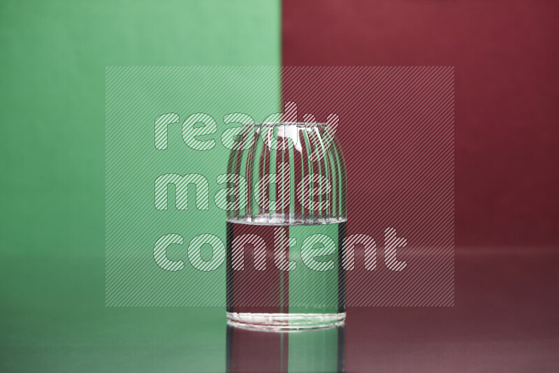 The image features a clear glassware filled with water, set against green and dark red background