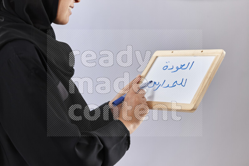 A woman in abaya holding books and a board in different positions (back to school)