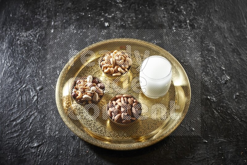 مكسرات في أطباق معدنية مع السوبيا على صينية علي خلفية سوداء