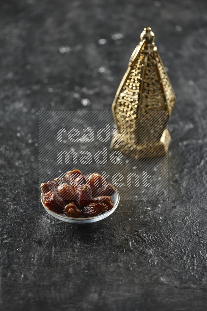 A golden lantern with different drinks, dates, nuts, prayer beads and quran on textured black background