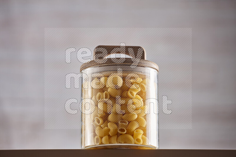 Raw pasta in glass jars on beige background