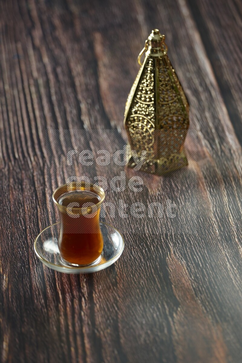 A golden lantern with different drinks, dates, nuts, prayer beads and quran on brown wooden background