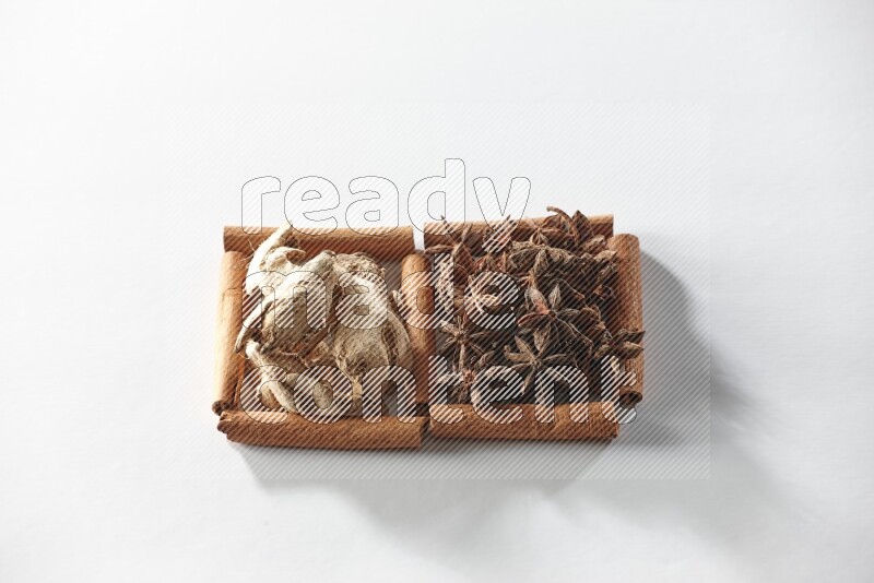 مربعان من أعواد القرفة ممتلئان باليانسون النجمي والزنجبيل المجفف علي خلفية بيضاء