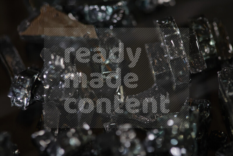 Transparent black fragments of glass scattered on a black background