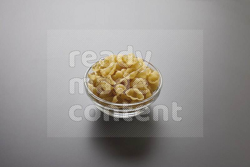 Snails pasta in a glass bowl on grey background