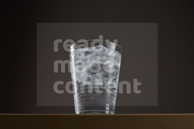 Low angle shot of a glass of water and ice on grey background