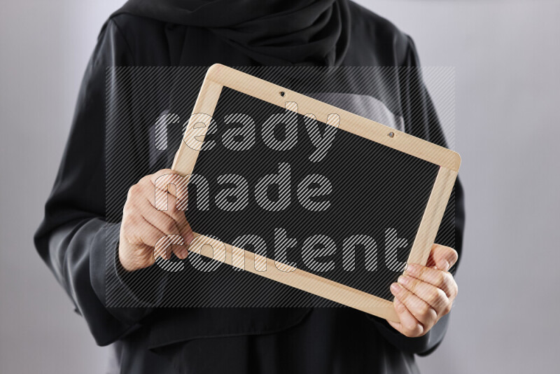 A woman in abaya holding books and a board in different positions (back to school)