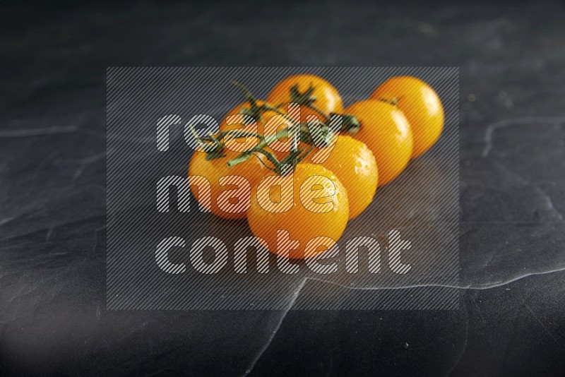 Yellow cherry tomato vein on a textured black slate background 45 degree