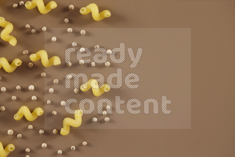 معكرونة مع مكونات متنوعة من الطماطم والثوم والبصل والفلفل الأحمر والفلفل الأسود والفلفل الأبيض وأوراق الغار وإكليل الجبل والهيل على خلفية بيج