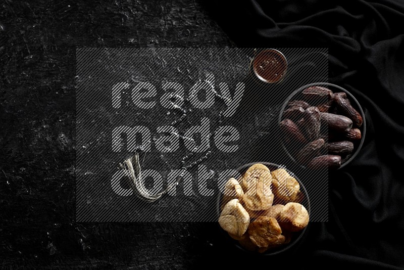 Dried fruits in pottery bowls with coffee in a dark setup