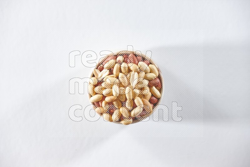 A beige ceramic bowl full of peeled peanuts on a white background in different angles