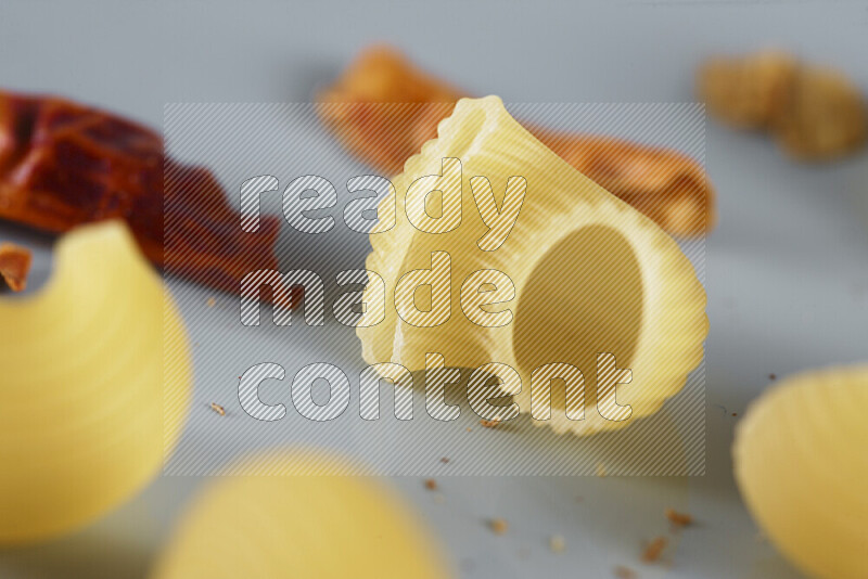 Raw pasta with different ingredients such as cherry tomatoes, garlic, onions, red chilis, black pepper, white pepper, bay laurel leaves, rosemary, cardamom and mushrooms on light blue background