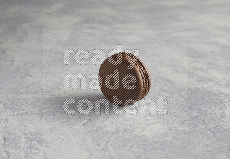 45º Shot of Brown Dark Chocolate macaron on white  marble background