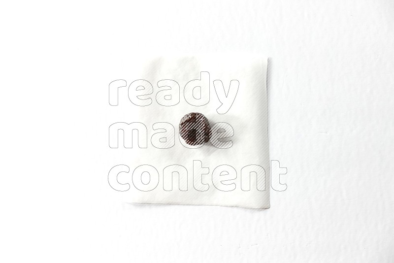 حبة واحدة من البرقوق المجفف على قطعة من الورق على خلفية بيضاء