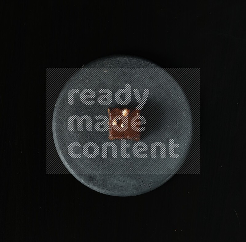 Assorted desserts in a black pottery plate on black background