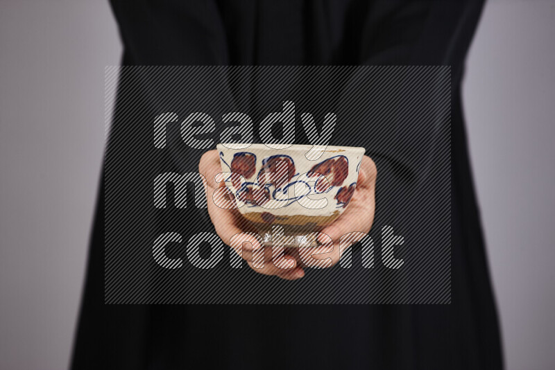 A woman in black abaya holding different pottery essentials in different positions