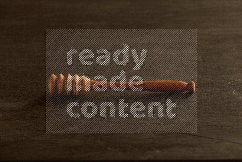 Wooden honey dipper on black slate background